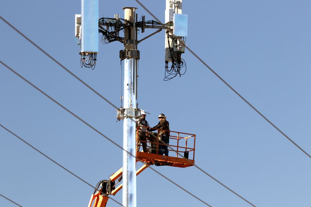 Technicians on a lift installing cable drop on a utility pole outdoors