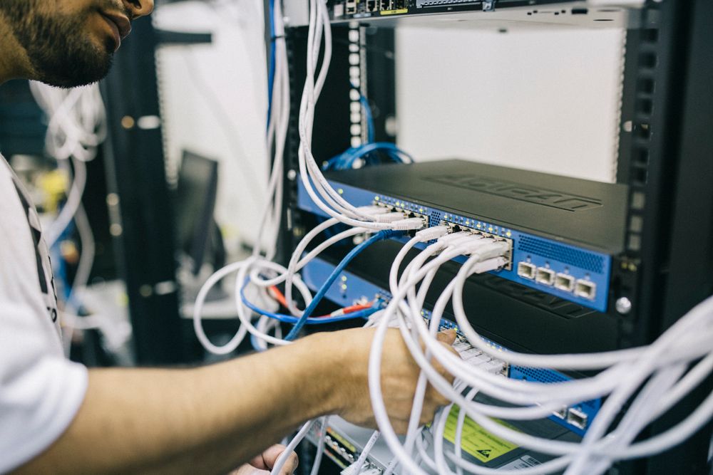 Technician installing network cables in a server rack